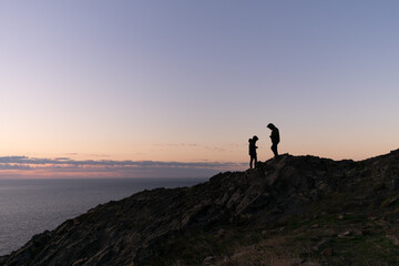 Silhouette of couple on mountain during sunrise.