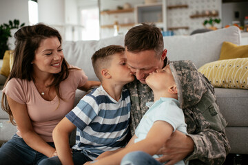 Obraz premium Happy soldier sitting on the floor with his family. Soldier and his wife enjoying at home with children