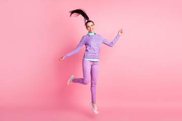 Fototapeta na wymiar Full length photo of cute girl jump wind blow hair wear violet pullover pants sneakers isolated pink color background