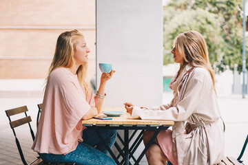 Two beautiful blond girls talking over breakfast.