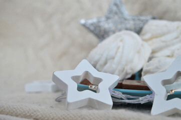 Handmade marshmallows and pieces of milk chocolate on a pale turquoise plate. Garland of white wooden stars, iron star on a knitted sweater background in cream color