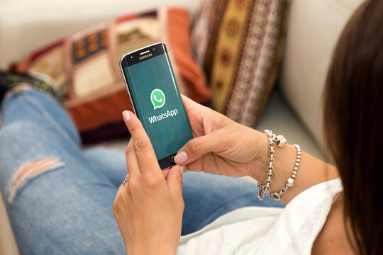 ROSARIO, ARGENTINA - OCTOBER 28, 2017: Young woman in resting in sofa with a smartphone with WhatsApp on the screen. Communications. Application.