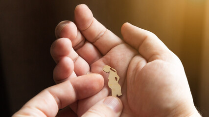 Silhouette figure of a pregnant woman lies on a man's hand