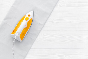 Yellow iron with clean linen on ironing board. Top view, copy space