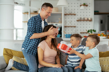 Two young sons are giving their mother a gift. Mother is suprised to receive a present from sons...