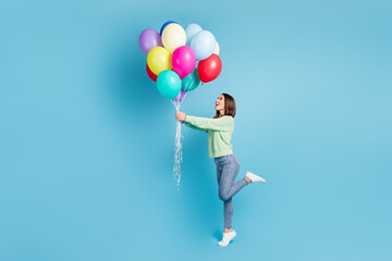 Fototapeta na wymiar Full length body size side profile photo of cheerful happy girl looking up standing tiptoe keeping balloons smiling isolated on vivid blue color background