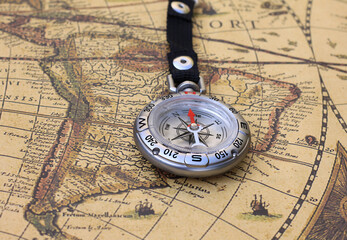Classic round compass on background of old vintage map of world as symbol of tourism with compass, travel with compass and outdoor activities with compass