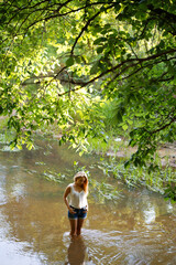 girl near the water of a small river in the forest