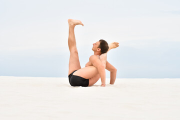 Man performs the pose of yoga on the beach