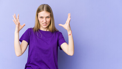 Young blonde woman isolated on purple background screaming with rage.