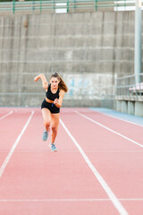 Fototapeta na wymiar Smiling fit female teenager runner training on running track