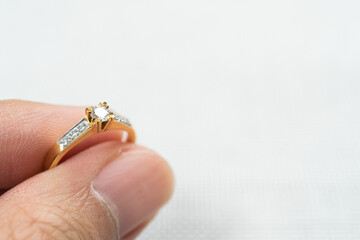 Man holding wedding diamond ring over white background.