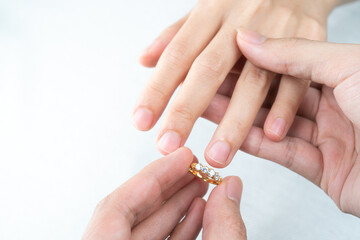 Man putting diamond ring on woman hand over white background.