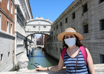 Fototapeta na wymiar young woman with mask and straw hat while visiting Venice and br