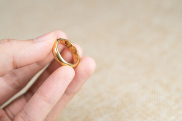 Man holding wedding ring over brown sack background.