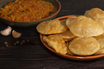 Indian cuisine. Luchi tortillas with cooked and fresh vegetables, Halwa Puri or Shira Poori. Wood background.