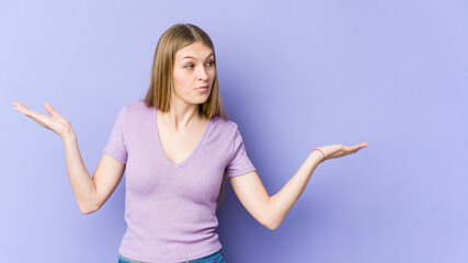 Young blonde woman isolated on purple background confused and doubtful shrugging shoulders to hold a copy space.