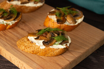 Baguette toast with soft cream cheese and mushrooms on a wooden Board. Snacks, quick breakfasts.