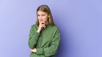 Young blonde woman isolated on purple background contemplating, planning a strategy, thinking about the way of a business.