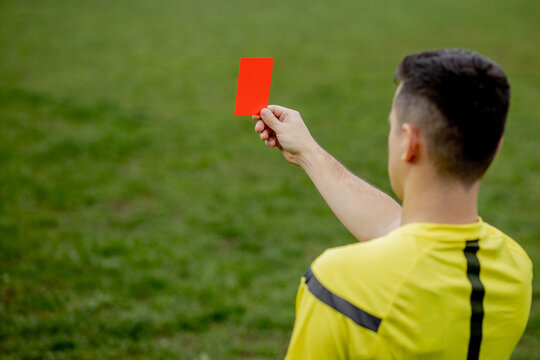 Referee showing a red card to a displeased football or soccer player while gaming. Concept of sport, rules violation, controversial issues, obstacles overcoming.