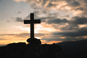 Silhouette of a cross on the mountain at sunset, hope concept.