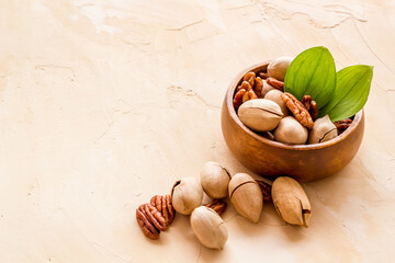Pecan nuts with leaves in bowl on the table, close up