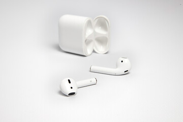 white wireless headphones with their case on white background