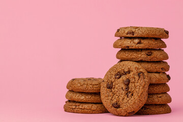Stacked chocolate chip cookies against pink background