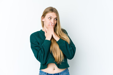 Young blonde woman isolated on white background thoughtful looking to a copy space covering mouth with hand.