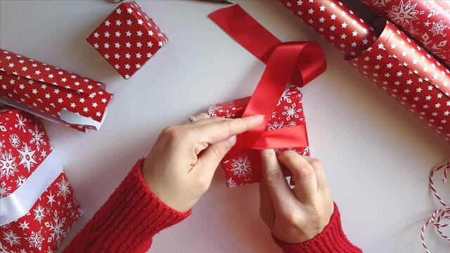 Woman ties a ribbon bow and wrapping presents
