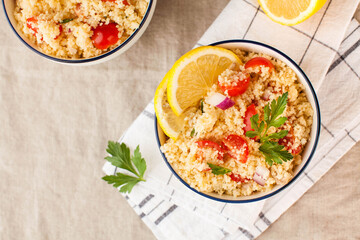 Flatlay Tabouleh is an Arabic vegetarian salad made with couscous, tomatoes, parsley, onion and lemon juice. Copy space.