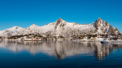 Fototapeta na wymiar Beautiful winter landscape with lake and steep mountains near Svolvaer on the Lofoten islands in Norway with snow on clear day with blue sky