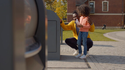 African father teaching cute preschool daughter throwing plastic bottle in recycling trash bin