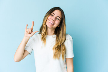 Fototapeta premium Young caucasian woman isolated on blue background showing a horns gesture as a revolution concept.