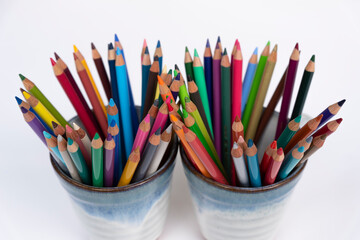 Colorful wooden crayons in mug for drawing and writing on white backgroud. Creativity collection in rainbow color for school and office.