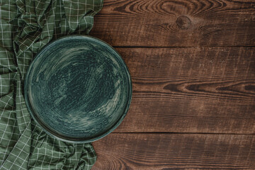 Vintage wooden table with green tea towel and empty plate. Beautiful background with copyspace. Restaurant concept.