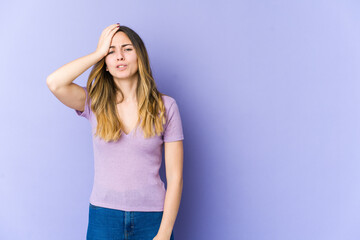 Young caucasian woman isolated on purple background forgetting something, slapping forehead with palm and closing eyes.