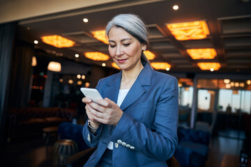 Charming businesswoman using modern smartphone in cafe