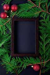 Christmas background with copy space. Wooden picture frame, thuja twigs and baubles around