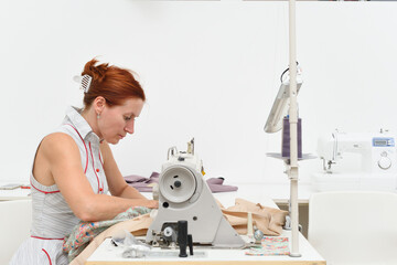 Middle aged woman works at a sewing machine in a sewing workshop