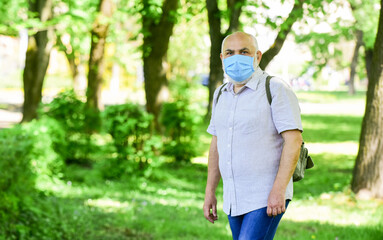 senior man in respirator mask. enjoy spring nature tree outdoor. coronavirus covid19. spring enjoyment. restricted public park. park is closed for quarantine due to coronavirus. copy space