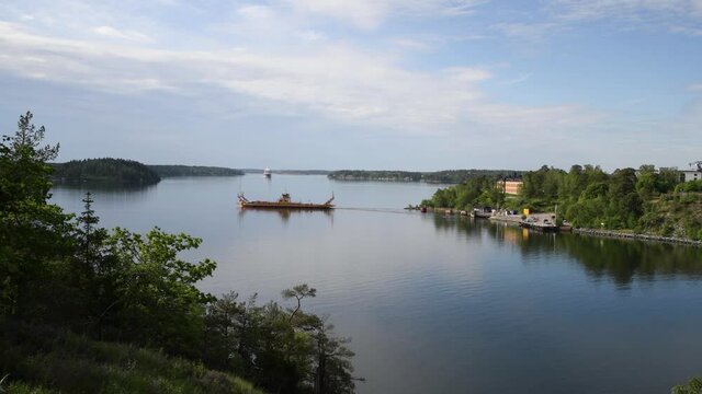 Car ferry passing the narrow passage Oxdjupet before the cruising ship from Stockholm to Finland pass by a sunny summer morning in the archipelago of Stockholm