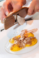 Alba white truffle sliced on Italian egg pasta ravioli by the waiter's hands