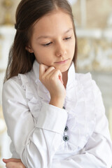 Portrait of cad little girl in white blouse posing at home