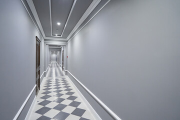 Empty long gray corridor in hotel with closed doors