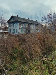 autumn landscape with an old and gloomy wooden house against a cloudy sky background