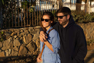 couple walking
holding hands and smiling on the Marbella beach in Spain with sunglasses