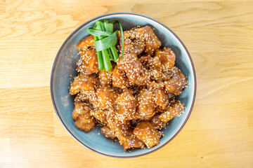 Honey chicken with noodles and vegetables, topped with sesame seeds.