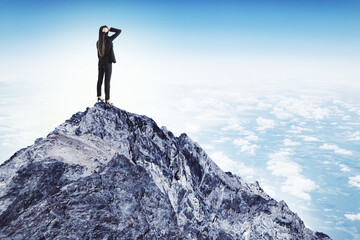 Young businesswoman in suit standing on mountain