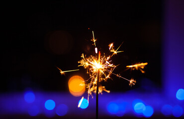 Sparks and fire on a black and blue background. Festive Merry Christmas sparklers. Golden Magic...
